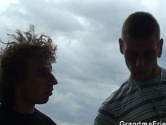 Amateur granny is seduced by two young guys. They jerk off and she doesn't think twice before blowing both of them. They end up fucking her right there outdoors.