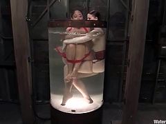 Petite Latin girl gets dominated by her mistress. She gets undressed and tied up. Later on she gets toyed with the strap-on from behind and tortured in an aquarium filled with cold water.