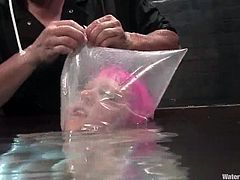 Nasty girl with pink hair gets tortured by her master in water bondage video. She gets tied up and choked in an aquarium.