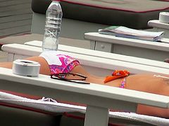 Blonde doll Charli Shiin is sun bathing on a deck chair on a yacht
