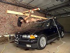 Tied up Asian girl lies on a BMW hood and gets her hairy pussy clothespinned. After that this girl gets whipped and watered with powerful jet of water.
