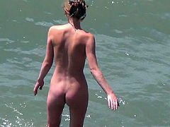 Skinny brunette is walking on the nudist beach