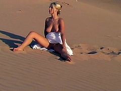 A sweet girl in a white dress lies on sand. She shows her juicy boobs and booty. Later on she takes the dress off and walks around.