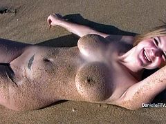 Curvaceous Danielle makes a solo show on the beach. Her body covered with sand looks hot. She poses for the camera lying on the ground.