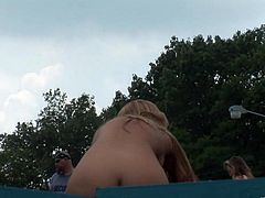 A hot blonde is having fun on the poolside in public. She strips and strokes her amazing body, then smears her body with some stuff and masturbates her pussy.