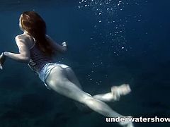 Nastya is a redheaded chick who sinks in the sea with clothes on and then she takes them off piece by piece. After she is completely naked, she swims freely.
