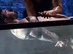 Take a look at this prick, he's tied in leather belts and submersed in a water tank. The water is cold and so is the heart of the executor that's punishing him merciless. The gay sex slave endures it all and the executor grabs him by the hair to take him out from the water for a breath and something special