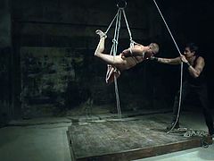 This gay slave hunk is tied up in rope and the master has hanged him from the ceiling. The slave has rope tightly wrapped around his cock and ball and the master give the rope a tug. This makes the gay slave sway back and forth.