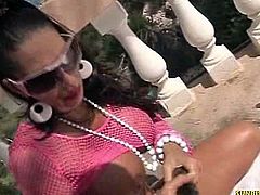This brunette chick is busty and she teases outdoors with her tanned pussy and ass. She sits on a butt plug and then she inserts a black dildo inside her cunt.