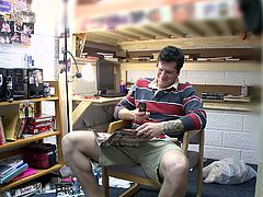 A hunky gay guy with short dark hair and a sexy tattooed body enjoys playing with his huge cock and balls in his bedroom.