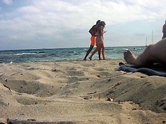 Women photographing nudist man at the beach